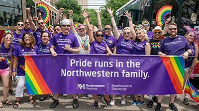 A parade of people posing with a large purple banner