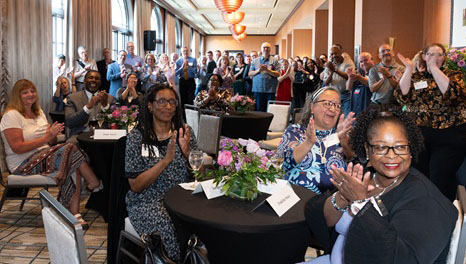 A wide lens view of the honoree's clapping during the recognition ceremony.